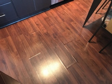Cost to replace buckling laminate floor due to leaking dishwasher.