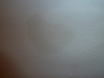 What could be causing these odd, slowly spreading stains on my bedroom ceiling?