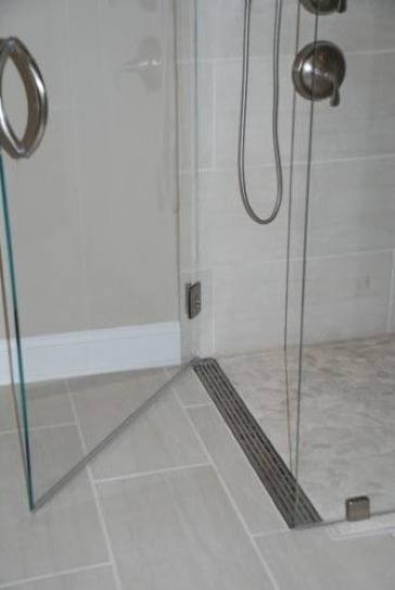 Should the linear drain be located against the far wall across from the shower door or would the drain by the doors work